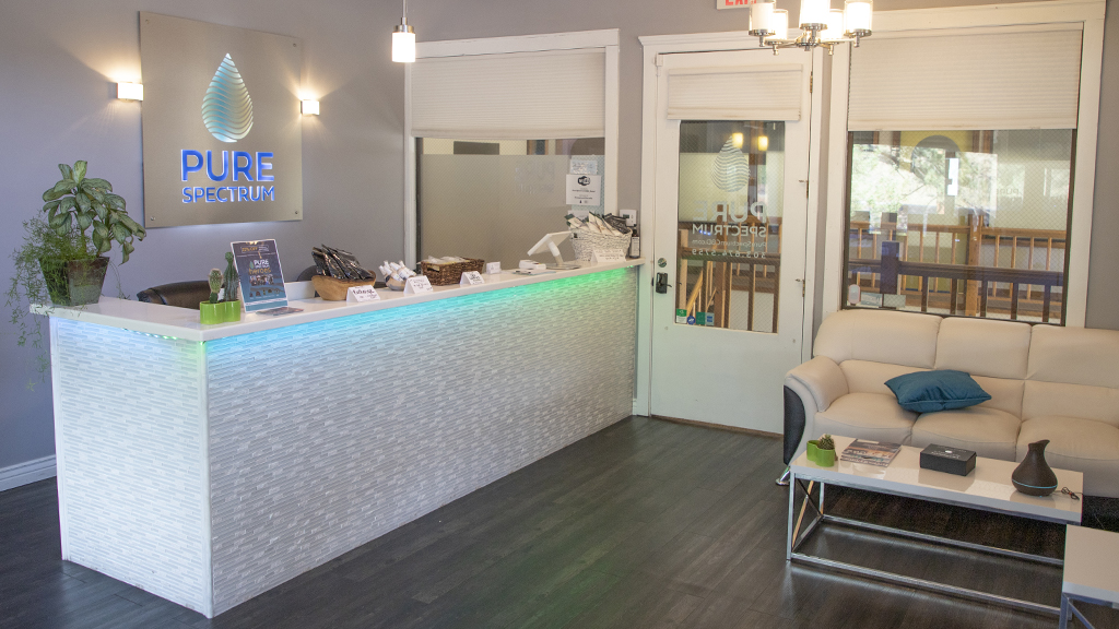 Interior of an attractive office reception area in light colors with the Pure Spectrum logo behind a tiled reception desk.