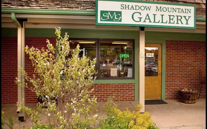 Exterior of a gallery in a brick building with a green open sign that is on.