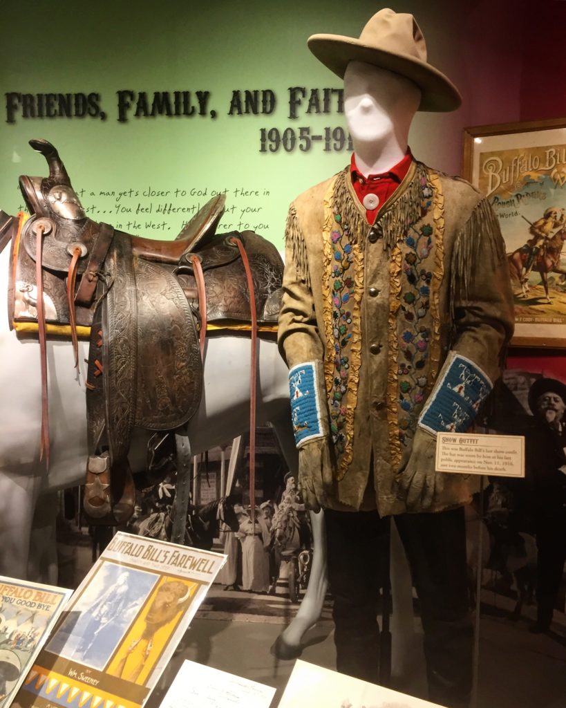 Interior image of an exhibit in the Buffalo Bill Museum with a display of clothing and a saddle on a morse mannequin. 