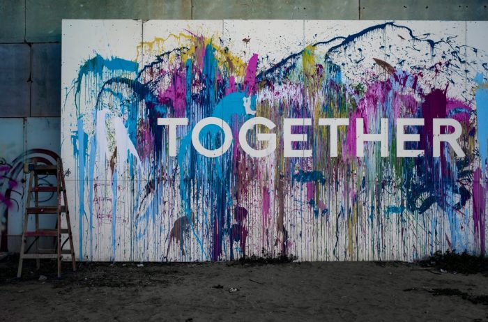 Artist studio with colorful splatter painting with the word "together" written on top.