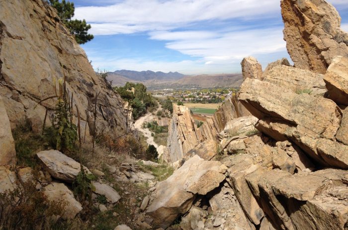 Large rock formations frame a town and mountains in the distance.