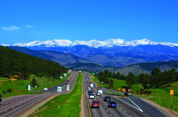 Three lane highway with beautiful mountain range in the distance. View from Genesee Park in Jefferson County, Colorado.