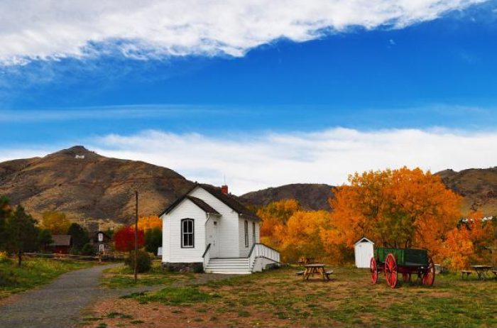 Small white historic building in Clear Creek History Park in Golden, Colorado in autumn with trees showing autumn color.