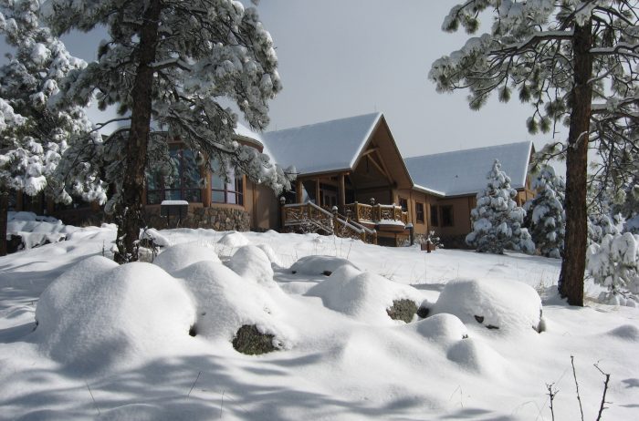 Mountain building with wood and stone accents on a winter day with snow covered ground and evergreen trees.