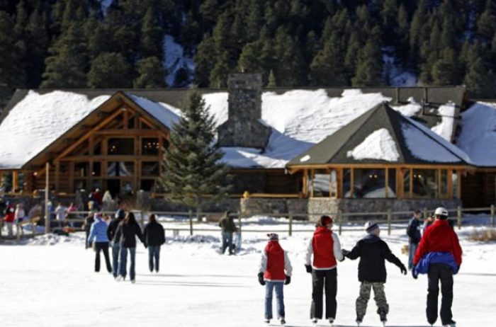 Families ice skating in the winter with a nice wood and stone building in the background. Evergreen Lake House in Evergreen, Colorado.