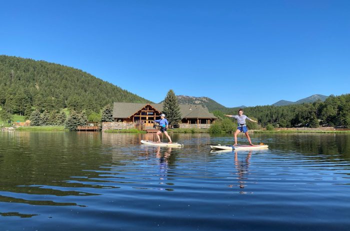 Two people doing stand up paddle boarding on Evergreen Lake in Colorado.