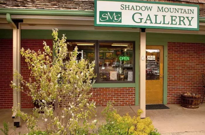 Exterior of a gallery in a brick building with a green open sign that is on.