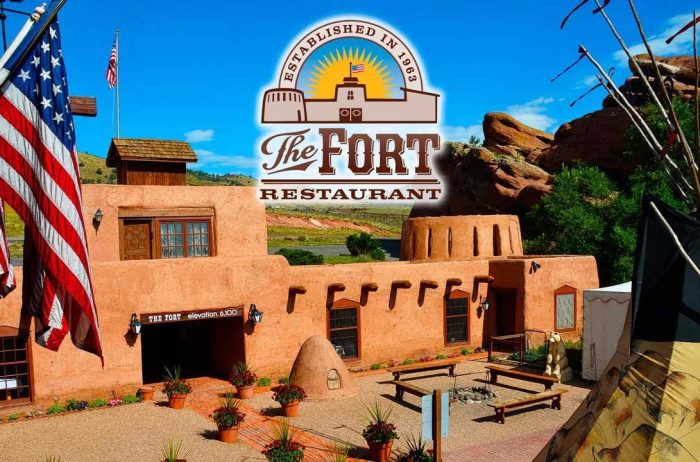 Exterior of an Adobe style building with American flags and the top of a teepee. Overlaid with the logo for the Fort Restaurant in Morrison, Colorado.